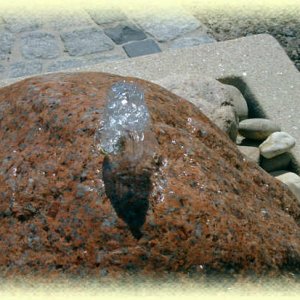 Roter       Granit- Quellstein auf beigem Zierkies in Livorno-Becken (Größe  80/80/35       cm)